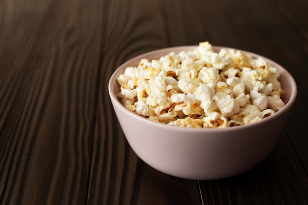 Bowl with popcorn on dark wooden table with copyspace