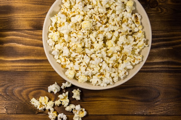 Bowl with popcorn on wooden table. Top view