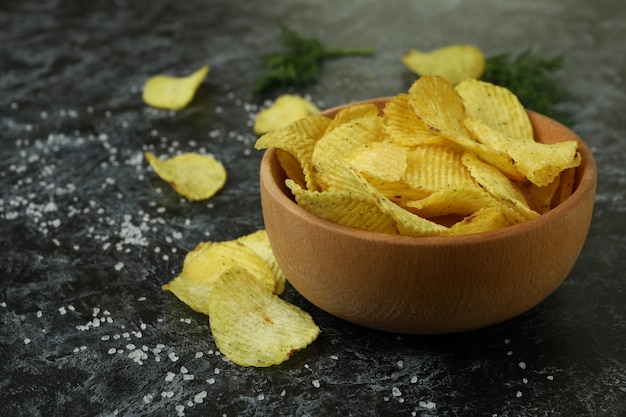 Bowl with potato chips on black smokey surface