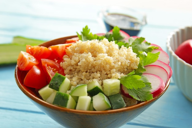 Bowl with quinoa and vegetables on table closeup