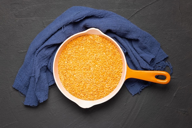 Bowl with red lentil on black background and blue kitchen towel