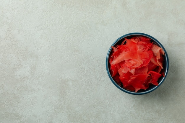 Bowl with red pickled ginger on white textured