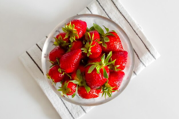 Bowl with red strawberries on a kitchen towel top view