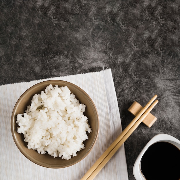 Bowl with rice on napkin near chopsticks and soy sauce