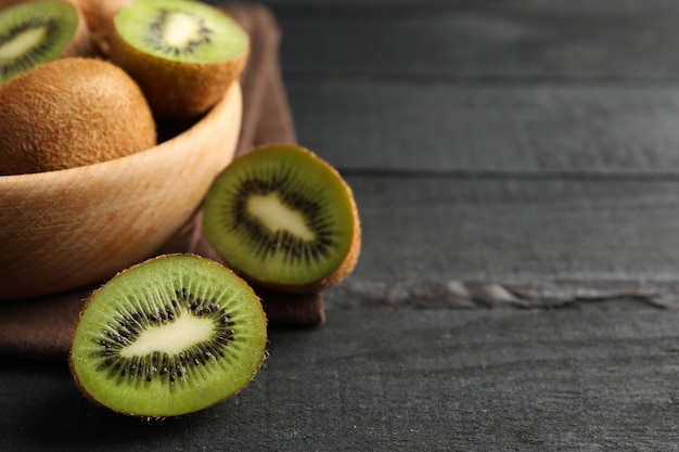 Bowl with ripe kiwi on wooden table