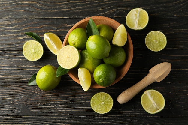 Bowl with ripe lime on wooden background, top view