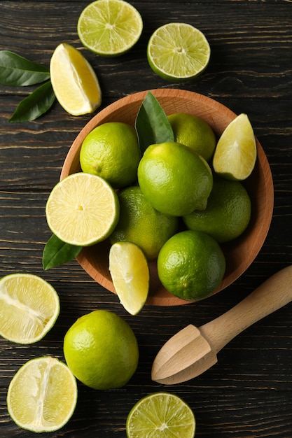 Bowl with ripe lime on wooden background, top view