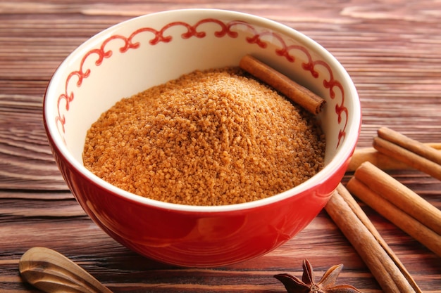 Bowl with sweet cinnamon sugar on wooden background