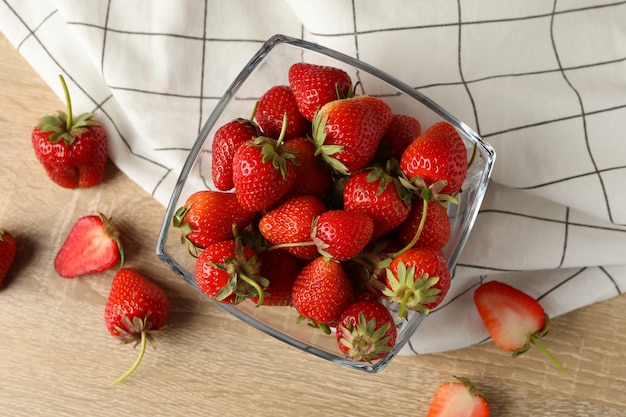 Bowl with tasty strawberry on wooden table. Summer berry