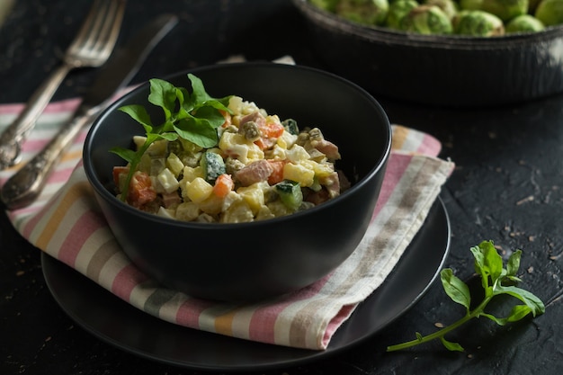 Bowl with traditional festive russian salad Olivier of sausage and vegetables with mayonnaise