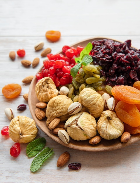 Bowl with various dried fruits and nuts on a wooden  surface