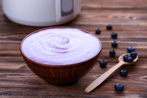 Bowl with yogurt and blueberries on wooden table