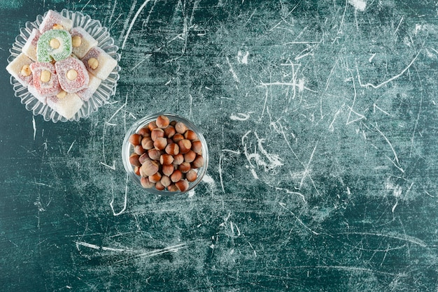 Bowls of organic hazelnuts and sweet delights on marble surface.