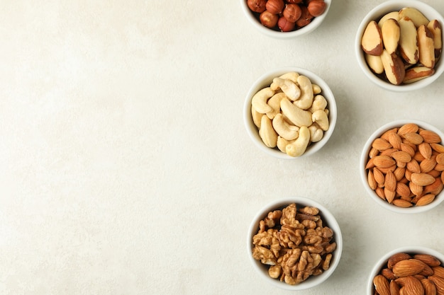 Bowls with different nuts on white textured