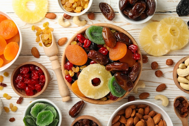 Bowls with dried fruits and nuts on white wooden table