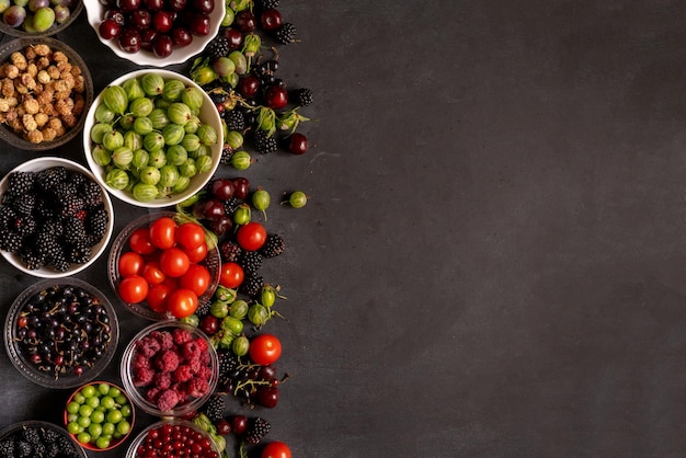 Bowls with fresh berries of cherry raspberry strawberry blackberry gooseberry mulberry and grape copy space