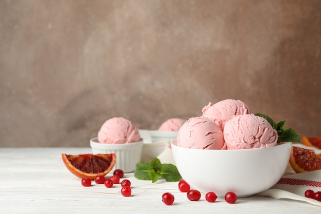 Bowls with ice cream balls on white wooden table