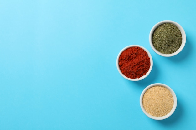 Bowls with red pepper, garlic and dill powder on blue, top view