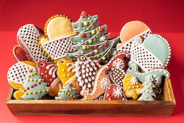 A box of Christmas Gingerbread on red background. Snowflake, fir tree, mitten, spruce, star, sleigh, cones, cone, star, bell shape.