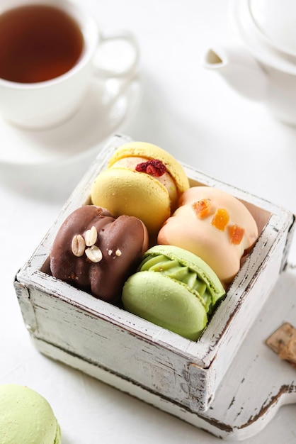 A box of different flavors of desserts and a cup of tea.