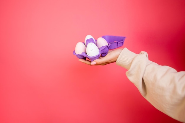 Box of light eggs in hand on pink background isolation