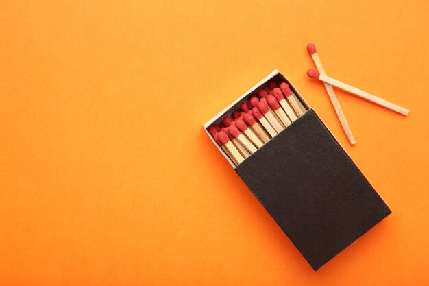 Box of matches with matches on orange background