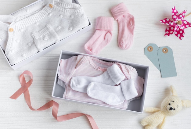 Box with baby stuff and accessories for newborn on white wooden background