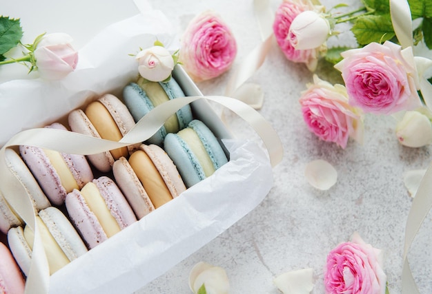 Box with delicious colorful macaroons and rose flowers