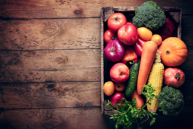 A box with fresh vegetables harvest fruits on an empty wooden table rustic background kitchen healthy food recipes organics and vitamins