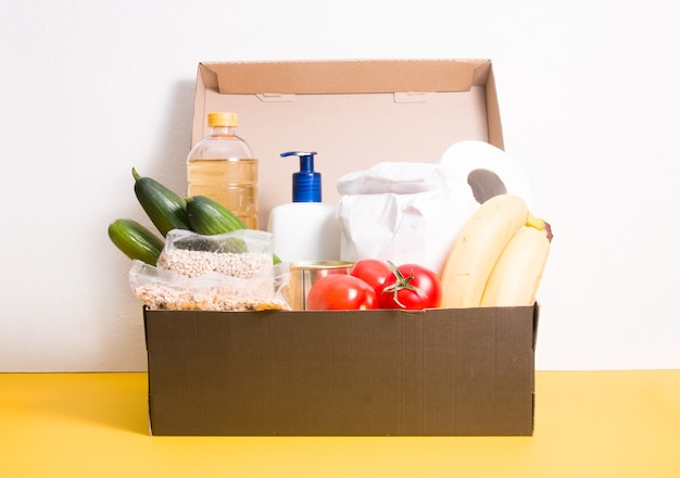 Box with products for donation on yellow surface