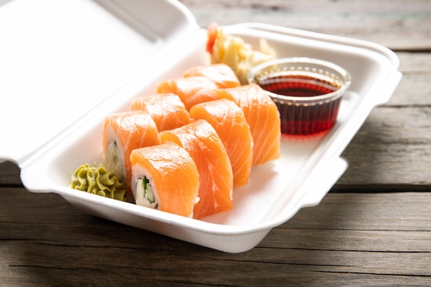 Box with rolls cream cheese soy sauce and wasabi on a wooden background. Japanese kitchen. Food delivery.