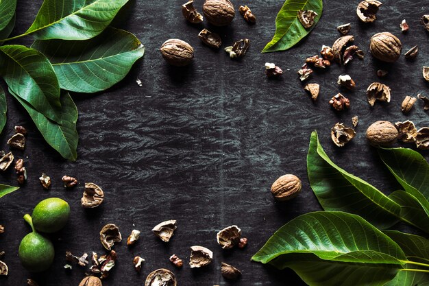 Box with tasty walnuts and nutcracker on dark wooden table, closeup