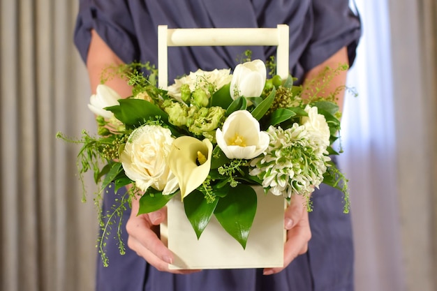 A box with white flowers in the hands of a woman Fresh beautiful flowers womens holiday Girl with flowers