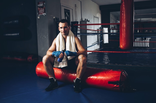 A boxer drinks water while training in a gym