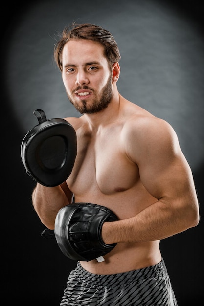 The boxer is a fighter, looking angrily at the camera. Young Caucasian male fitness model isolated on black background.