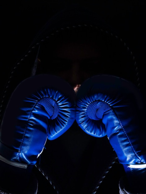 Boxer silhouette in hood Handsome athletic man in boxing stand on a dark background