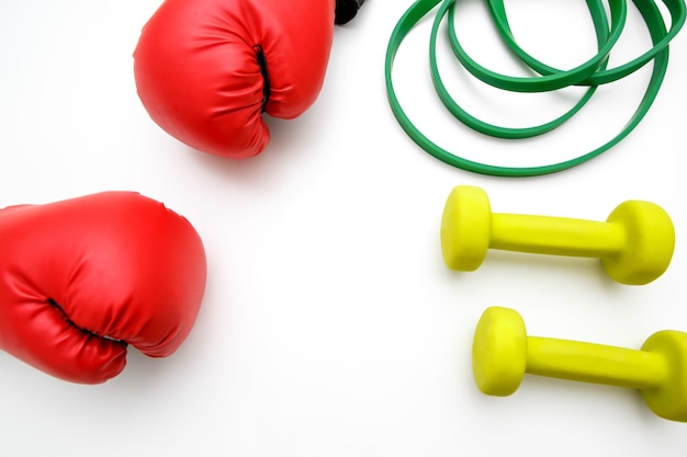 Boxing gloves small dumbbells and elastic band on a light background