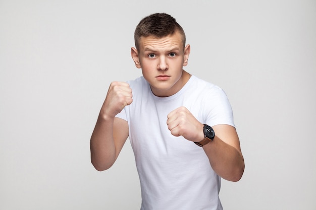 Boxing. Young anger man, ready to fight. Studio shot, gray wall