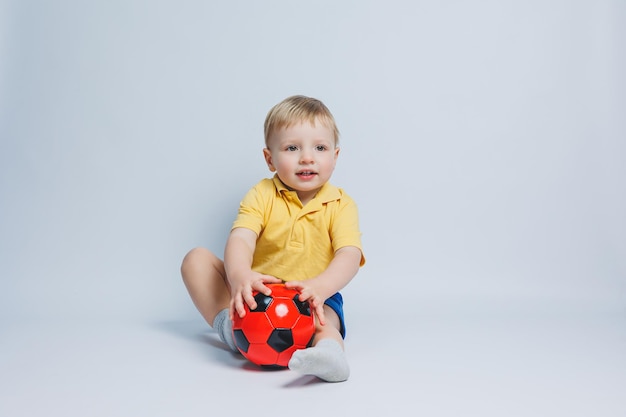 Boy 34 years old football fan in a yellow Tshirt with a ball in his hands holding a soccer ball in his hands isolated on a white background The concept of sports family recreation