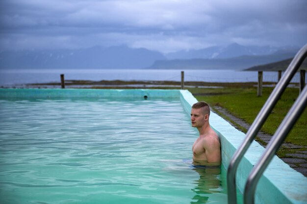 Boy bathes in reykjafjardarlaug hot pool located in the westfjords iceland