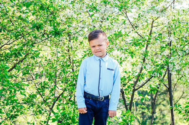 A boy in a blue shirt against the background of flowering trees