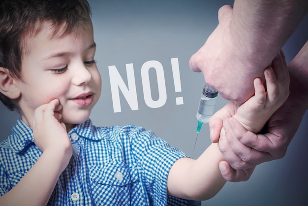 Boy in the blue shirt during vaccination with an inscription NO