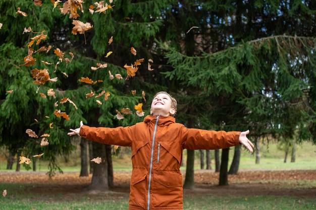 A boy catches autumn yellow leaves that fly at him