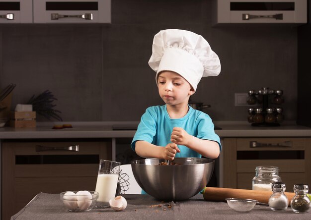 Boy in chef hat cooking in the kitchen