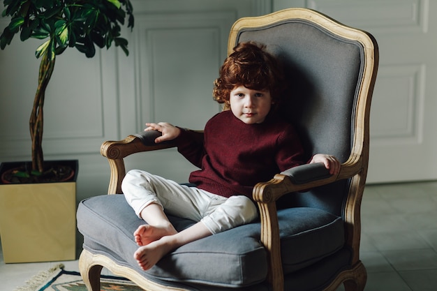 Boy child in casual clothes posing in the armchair