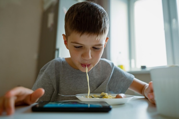 Boy child eats pasta sucking long pasta into his mouth