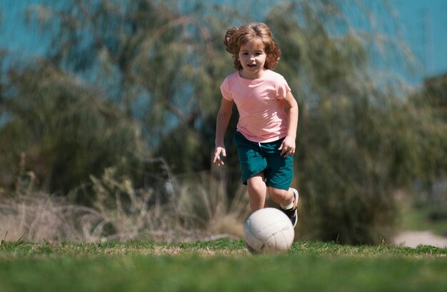 Boy child playing football on football field kid playing soccer child soccer play football in park