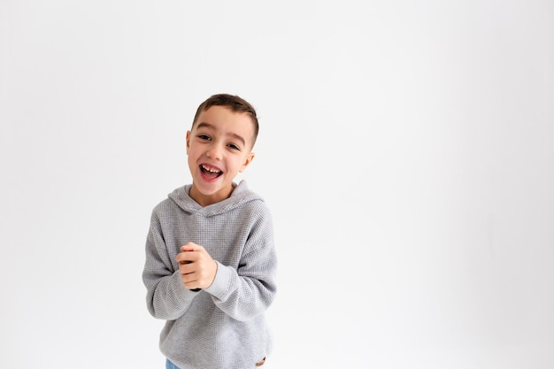 Boy child preschooler smiling and posing on gray background in photo studio