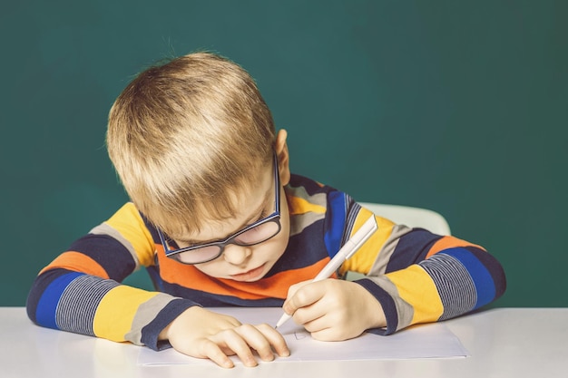 Boy child with glasses diligently writes Closeup