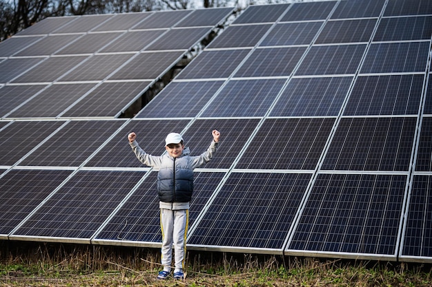 Boy child with hands up on the background of solar panels Eco energy